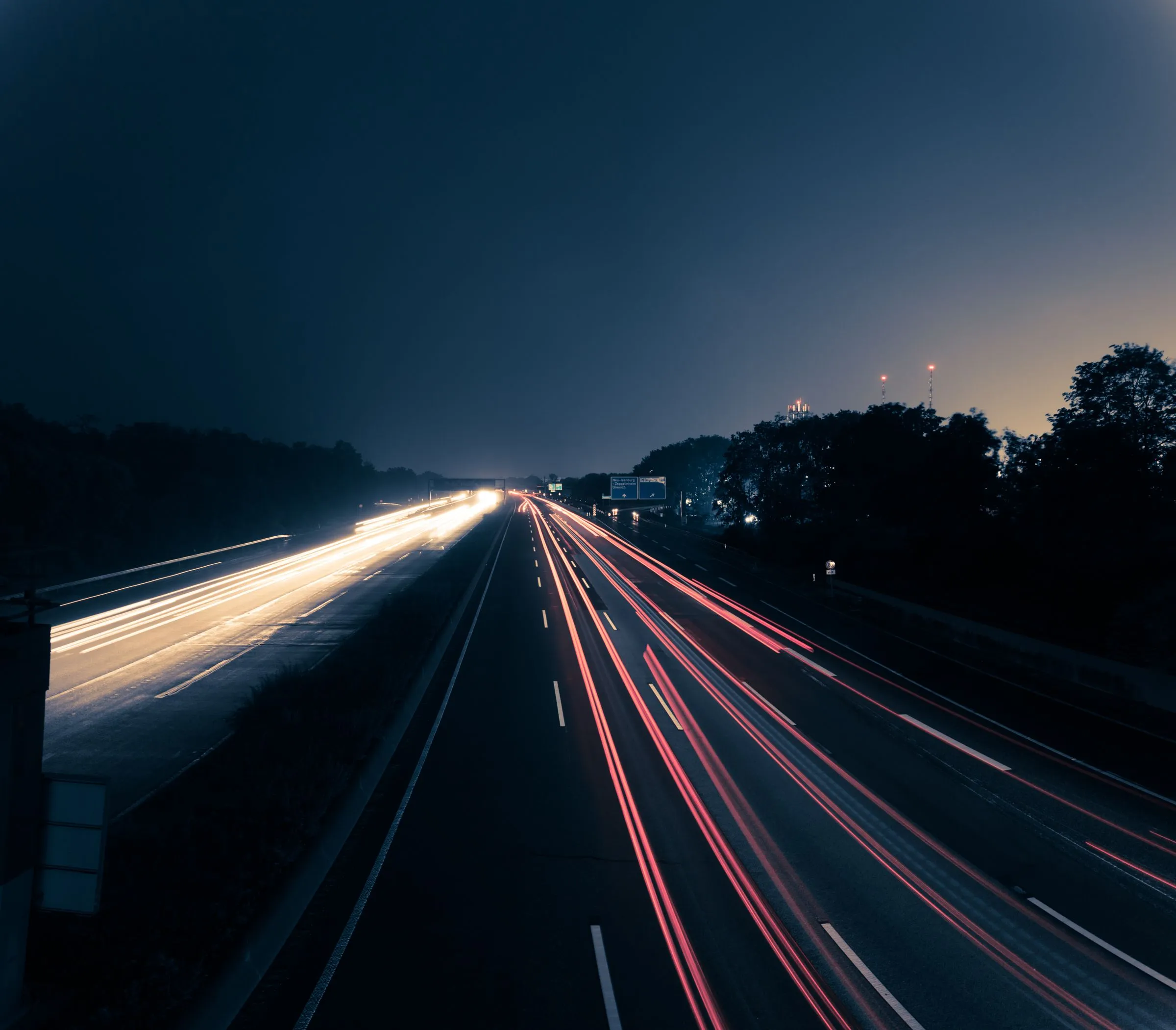 A highway at night, streaked with headlight and taillight trails